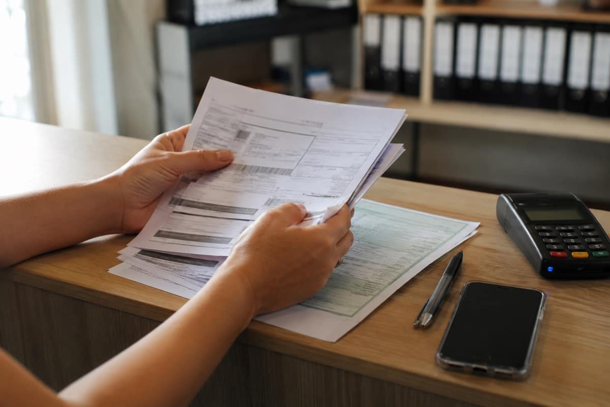 Cliente confere boletos e documento do veículo antes de pagar as taxas da transferência de propriedade