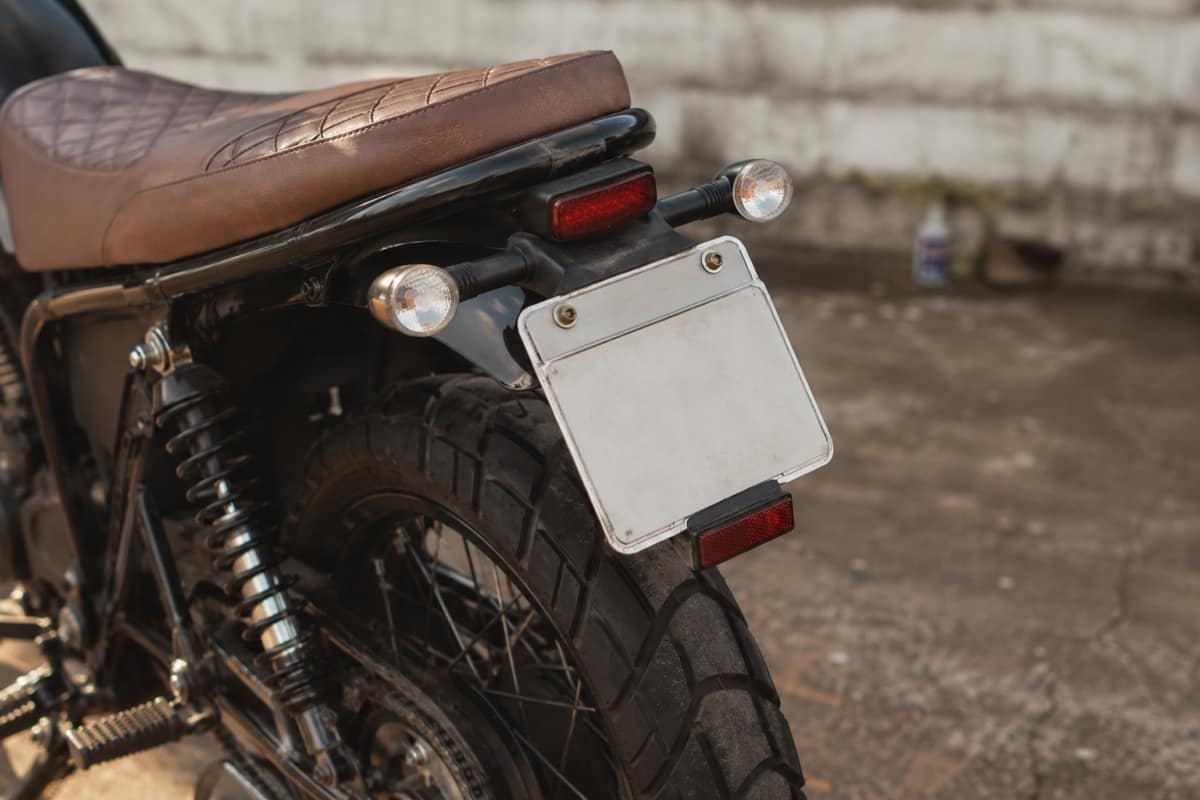 Motocicleta estacionada mostrando o suporte da placa traseira instalado abaixo do banco