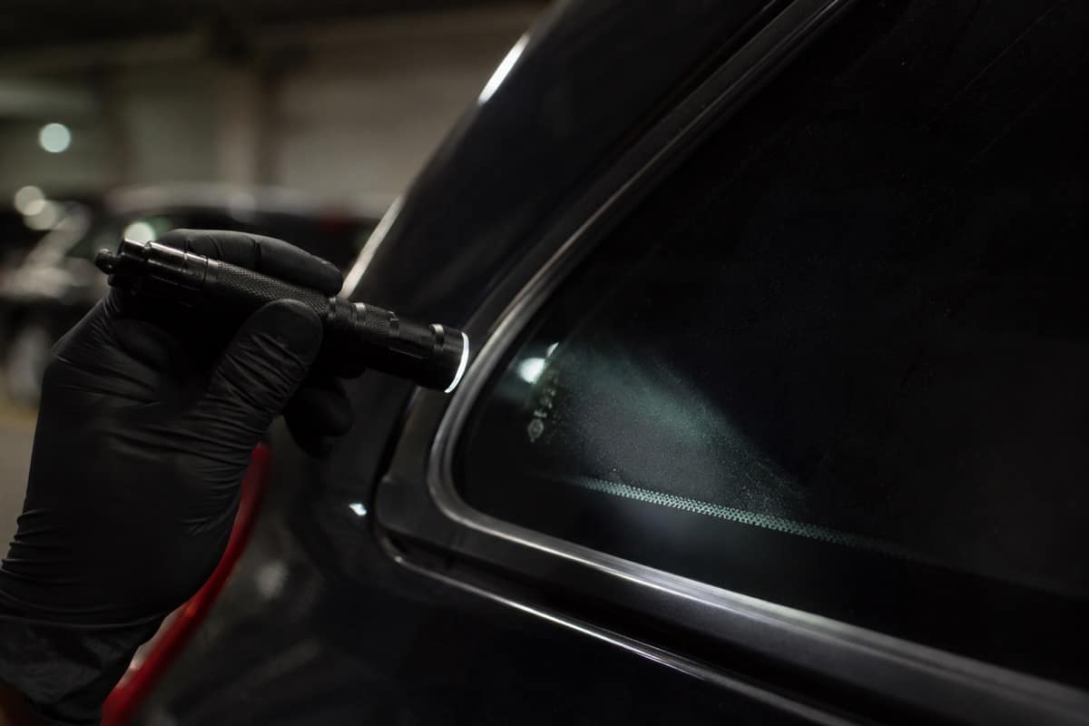 Close da gravação de identificação no vidro do carro sendo verificada com lanterna